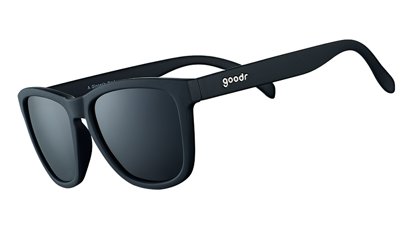 Three-quarter angle view of square-framed black sunglasses with black lenses on a white background.