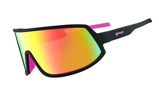 Three-quarter angle view of wraparound sunglasses with black frames with hot pink inner silicone grips, and a big pink lens. 