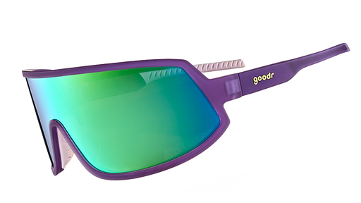 Three-quarter angle view of wraparound sunglasses with a reflective green lens and purple frames with white silicone inner grips.